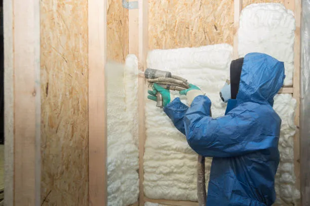 Installer in protective clothing spraying foam into wall cavities