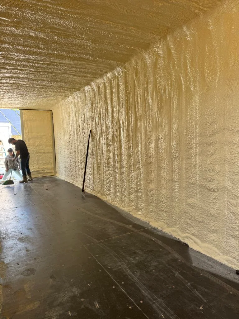 Closed-cell spray foam coating the walls and ceiling of a long building interior